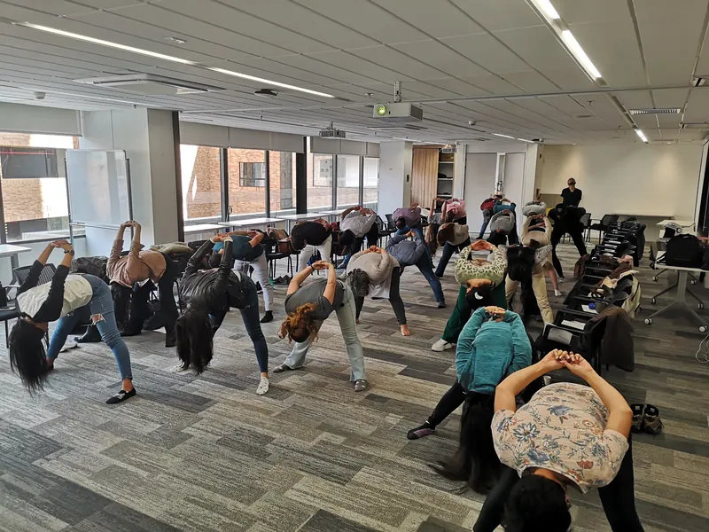 Grupo haciendo estiramientos de pie en una sala de reuniones