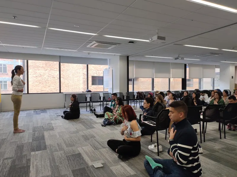 Grupo sentado en una sala de oficina siguiendo una práctica de respiración guiada