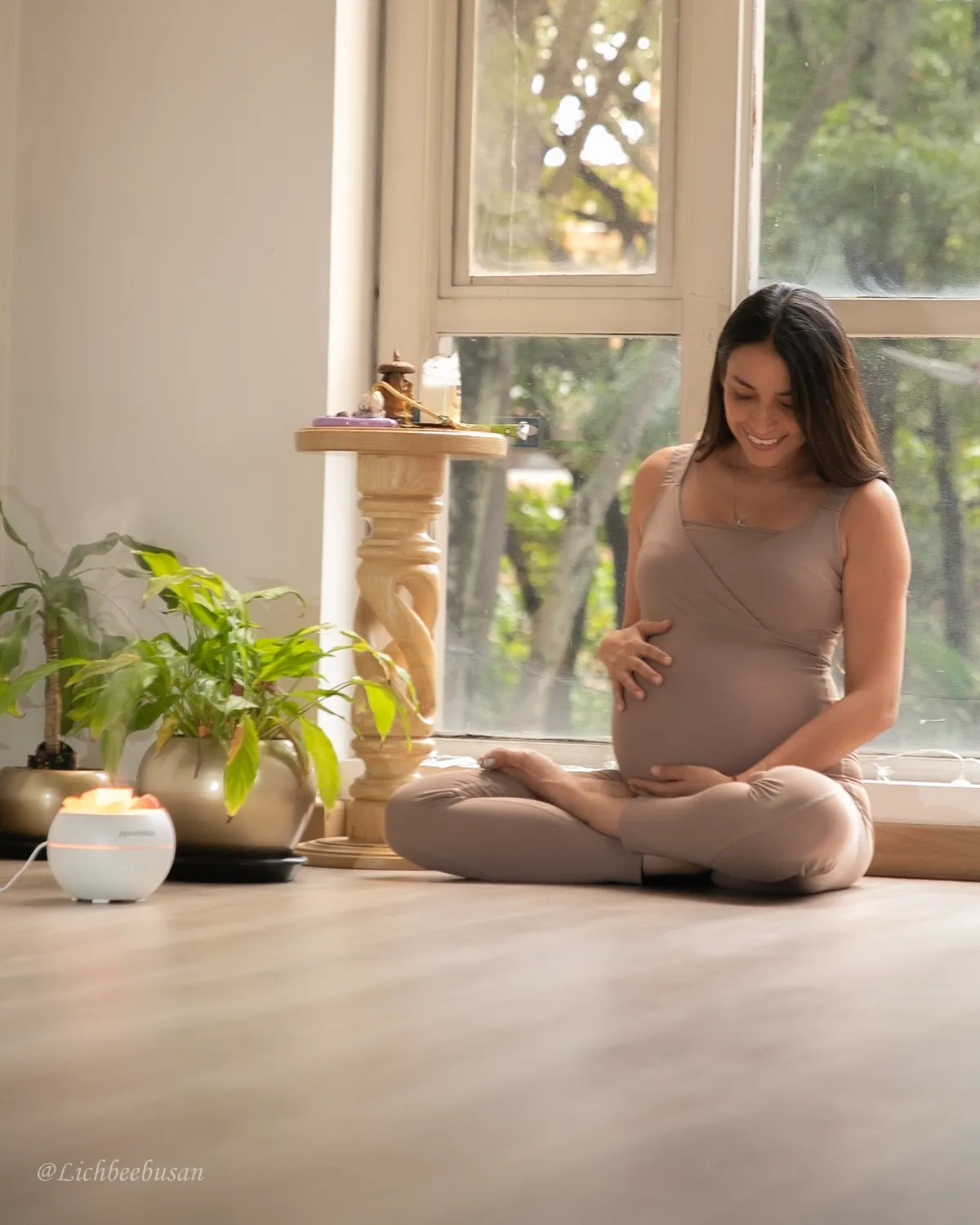 Mujer embarazada sentada junto a una ventana en el estudio de Atmaia Yoga